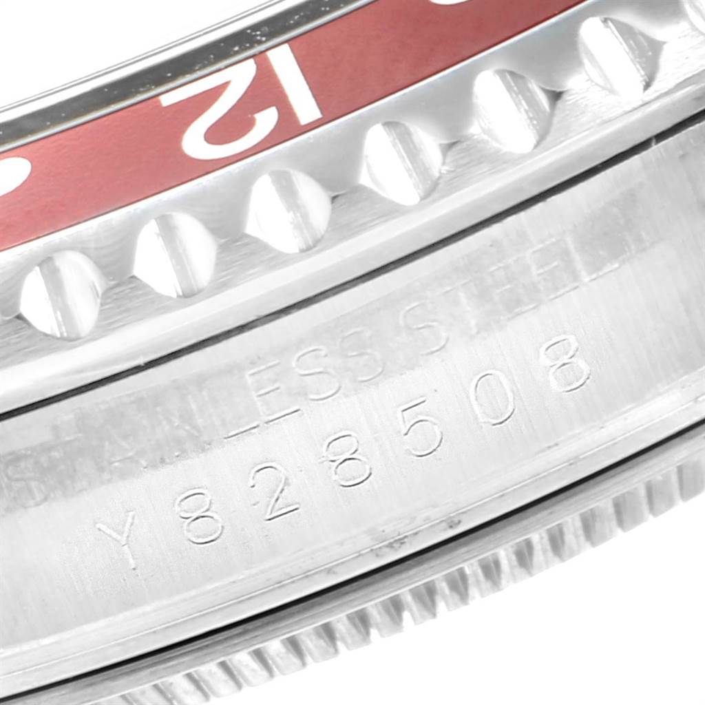 This close-up image of a Rolex GMT-Master 16710 Men's Stainless Steel Black Dial 16710 Men's Stainless Steel Black Dial watch shows part of the bezel with the "12" marker and the etched serial number on the stainless steel case.