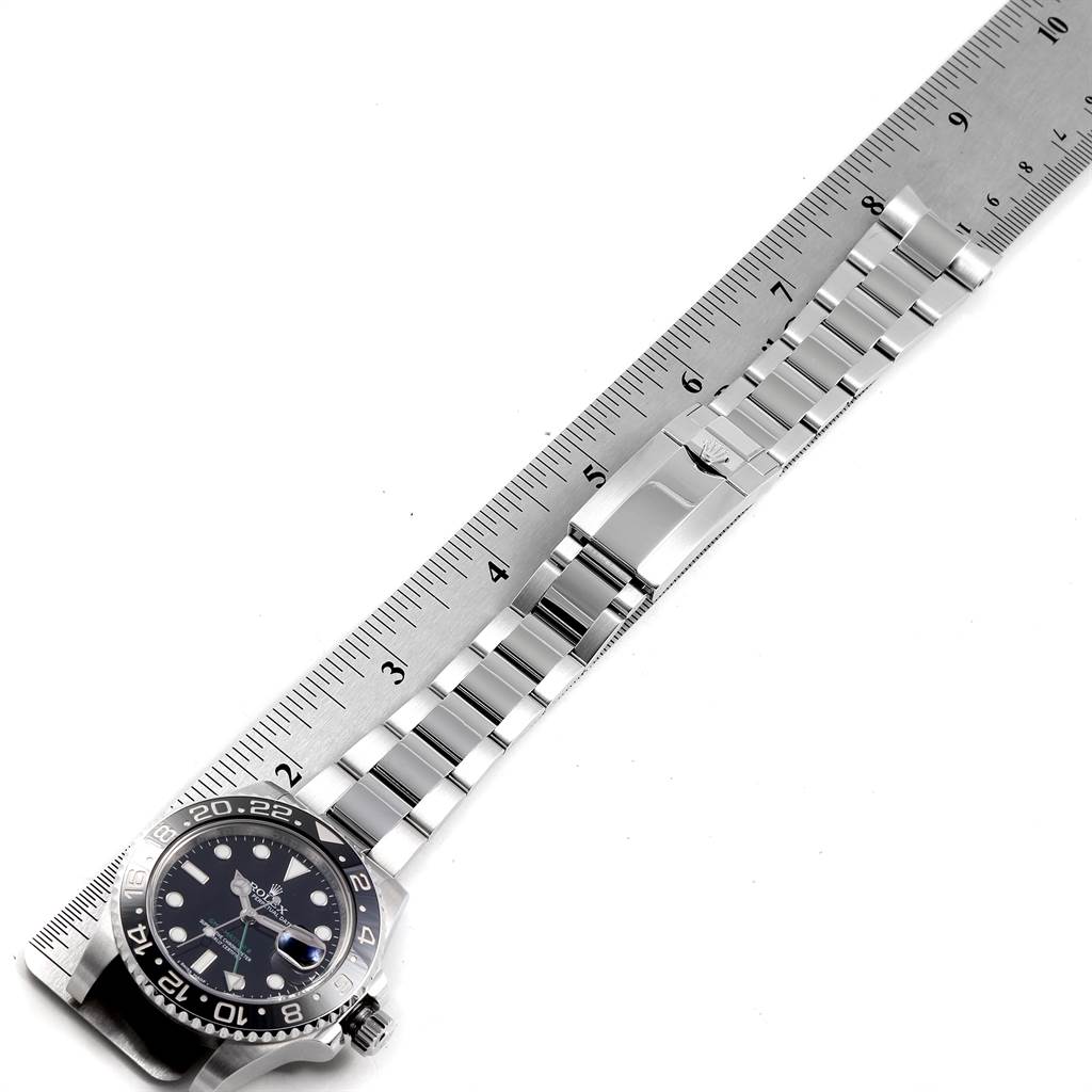 The image shows a Rolex GMT-Master 116710 Men's Stainless Steel Black Dial 116710 Men's Stainless Steel Black Dial watch from an overhead angle, highlighting the face, bracelet, and clasp superimposed on a measuring ruler.