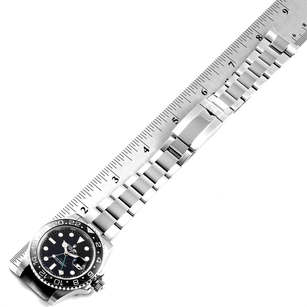 This image shows a Rolex GMT-Master 116710 Men's Stainless Steel Black Dial 116710 Men's Stainless Steel Black Dial watch and its bracelet laid flat against a ruler, viewed from above.