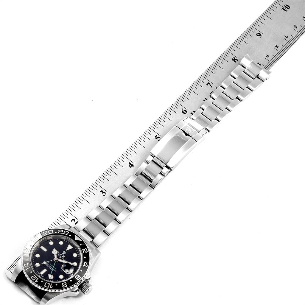 The image shows a top-down view of a Rolex GMT-Master 116710 Men's Stainless Steel Black Dial 116710 Men's Stainless Steel Black Dial watch with a metal bracelet laid beside a ruler.