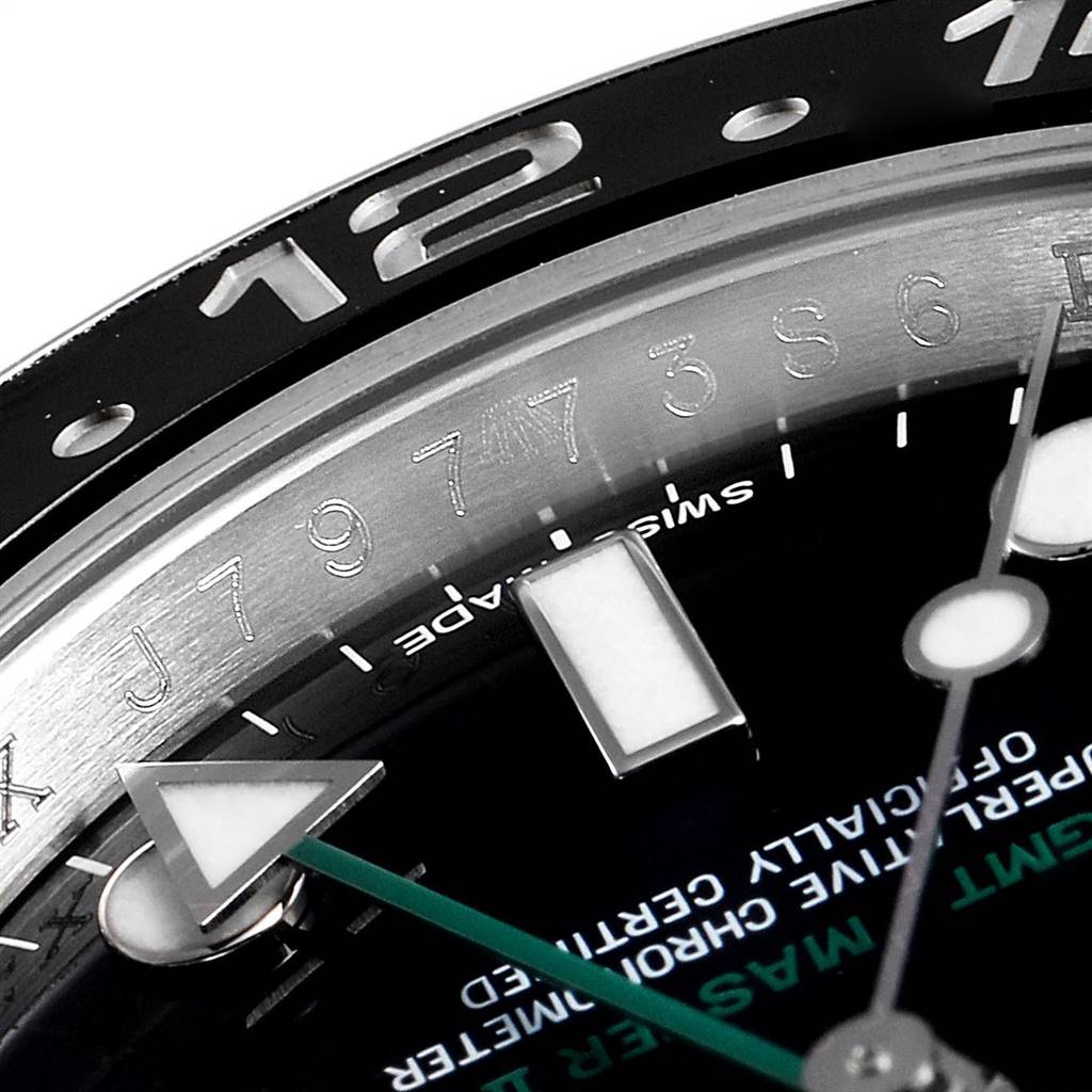 This close-up image of a Rolex GMT-Master 116710 Men's Stainless Steel Black Dial 116710 Men's Stainless Steel Black Dial watch shows part of the bezel, dial, and hands at an oblique angle.