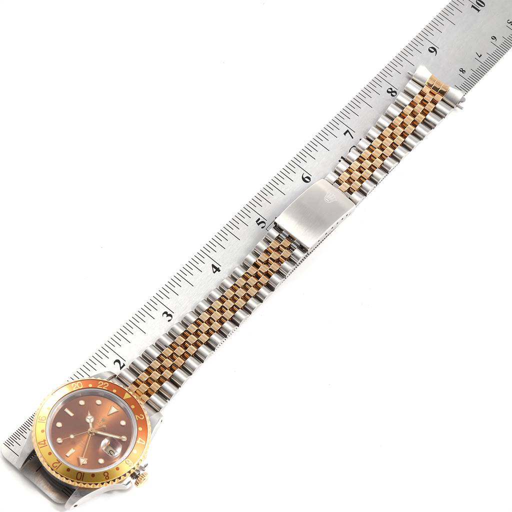 The Rolex GMT-Master 16713 Men's Stainless Steel Brown Dial 16713 Men's Stainless Steel Brown Dial watch is shown laid flat with its face and bracelet visible, alongside a ruler for size reference.
