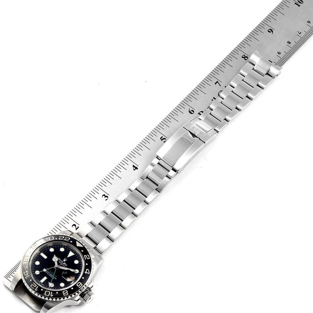 The image shows a Rolex GMT-Master 116710 Men's Stainless Steel Black Dial 116710 Men's Stainless Steel Black Dial watch laid flat with a focus on its face, bezel, and metal bracelet next to a ruler.