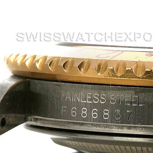 This image shows a close-up of the side of a Rolex GMT-Master 16713 Men's Stainless Steel Brown Dial 16713 Men's Stainless Steel Brown Dial, highlighting the stainless steel case, engraved serial number, and gold bezel.