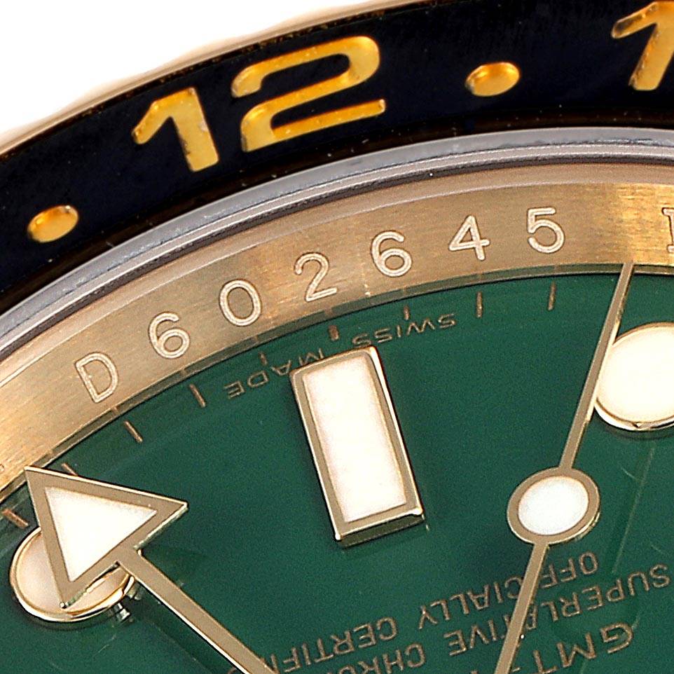 The image shows a close-up of the dial and bezel of a Rolex GMT-Master 116718 Men's Yellow Gold Green Dial 116718 Men's Yellow Gold Green Dial, highlighting the 12 o'clock marker and part of the minute hand.