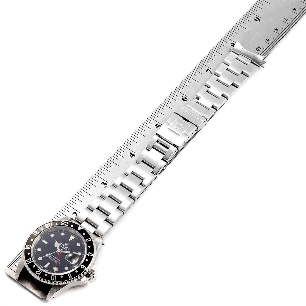 The image shows a Rolex GMT-Master 16700 Men's Stainless Steel Black Dial 16700 Men's Stainless Steel Black Dial watch placed next to a ruler, highlighting its stainless steel bracelet and clasp from an overhead angle.