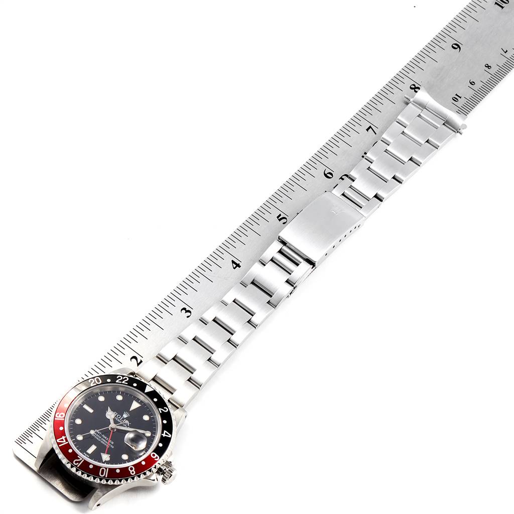 The image shows a Rolex GMT-Master 16700 Men's Stainless Steel Black Dial 16700 Men's Stainless Steel Black Dial watch laid flat, highlighting the watch face, bezel, crown, and stainless steel bracelet against a ruler.