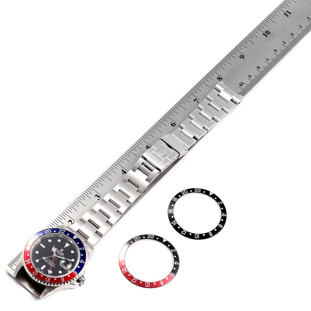 The image shows a Rolex GMT-Master 16710 Men's Stainless Steel Black Dial 16710 Men's Stainless Steel Black Dial watch with its band next to a ruler, along with two additional bezels.