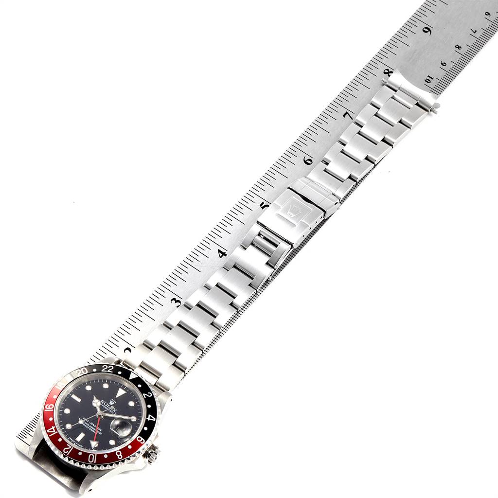 The image shows a Rolex GMT-Master 16700 Men's Stainless Steel Black Dial 16700 Men's Stainless Steel Black Dial watch placed next to a metal ruler, viewed from above, highlighting the watch face, bezel, and bracelet.