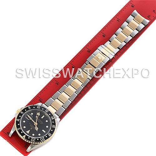 The image shows a top-down view of a Rolex GMT-Master 16713 Men's Stainless Steel Black Dial 16713 Men's Stainless Steel Black Dial watch, including the bezel, face, and metal bracelet, with a red ruler beneath.