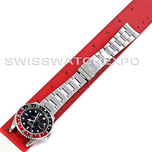 This top-down image shows the entire Rolex GMT-Master 16710 Men's Stainless Steel Black Dial 16710 Men's Stainless Steel Black Dial watch, including the face, bezel, bracelet, and clasp laid out against a red ruler.