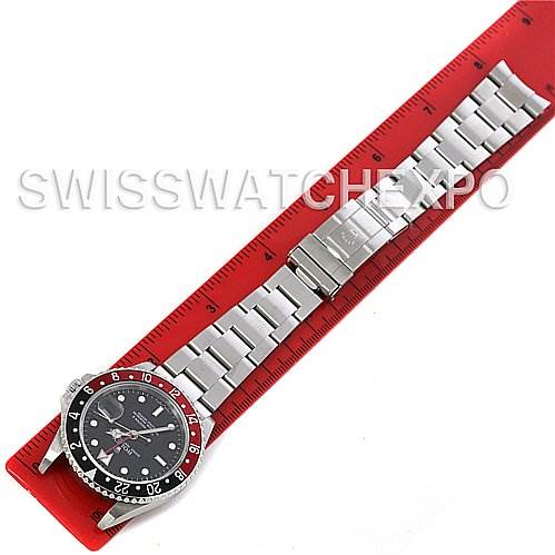 This image shows a top-down view of a Rolex GMT-Master 16710 Men
s Stainless Steel Black Dial 16710 Men
s Stainless Steel Black Dial watch, highlighting the bezel and metal bracelet on a red measuring scale.