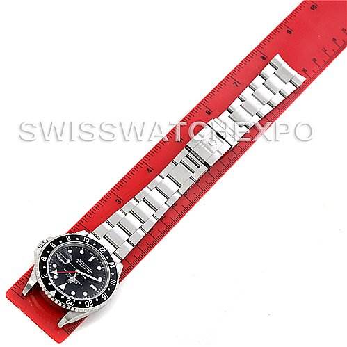 The image shows a top-down view of a Rolex GMT-Master 16710 T Men's Stainless Steel Black Dial 16710 T Men's Stainless Steel Black Dial watch, including the watch face and entire metal bracelet, next to a red ruler.