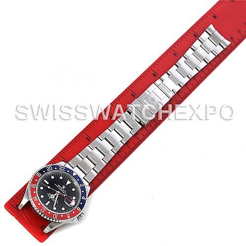 The Rolex GMT-Master 16710 Men's Stainless Steel Black Dial 16710 Men's Stainless Steel Black Dial watch is shown from a top-down angle, displaying the bezel, dial, and metal bracelet against a measuring ruler.