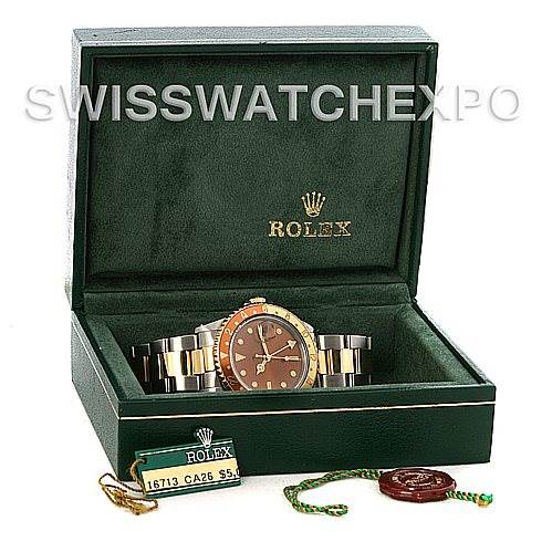 The image shows a Rolex GMT-Master 16713 Men
s Stainless Steel Brown Dial 16713 Men
s Stainless Steel Brown Dial watch in its open green box, accompanied by a tag and seal, viewed at a front angle.