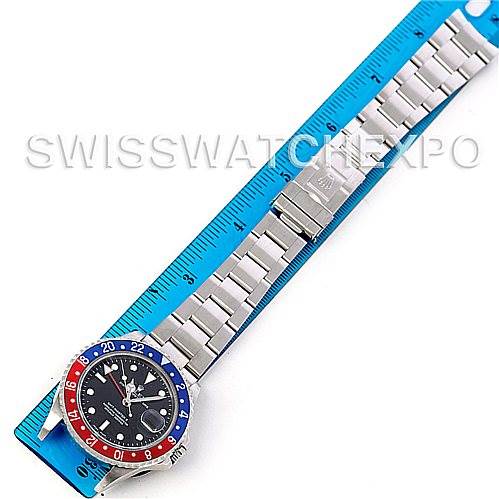The image shows a top view of a Rolex GMT-Master 16710 Men's Stainless Steel Black Dial 16710 Men's Stainless Steel Black Dial watch with a "Pepsi" bezel, alongside a blue ruler for scale.