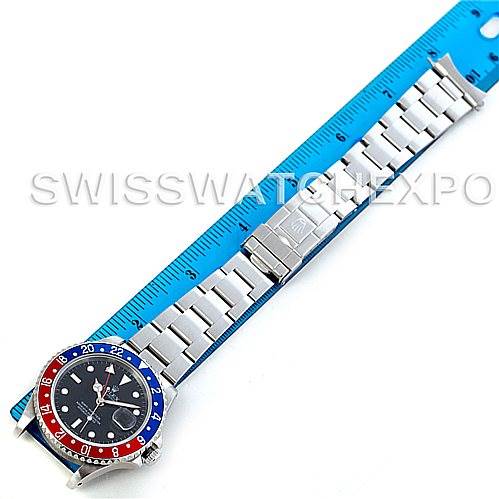 This is a top view of a Rolex GMT-Master 16700 Men's Stainless Steel Black Dial 16700 Men's Stainless Steel Black Dial watch showing the dial, bezel, and bracelet placed alongside a blue ruler.