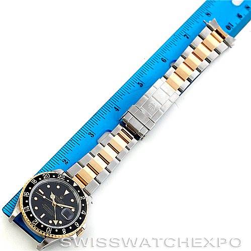 The image shows a Rolex GMT-Master 16713 Men's Stainless Steel Black Dial 16713 Men's Stainless Steel Black Dial watch, featuring the face, bezel, and two-tone bracelet with a blue ruler for size reference.