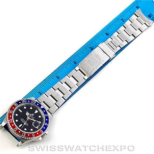 The image shows a top view of a Rolex GMT-Master 16710 Men's Stainless Steel Black Dial 16710 Men's Stainless Steel Black Dial watch, including the face, bezel, and full metal bracelet, positioned beside a ruler.