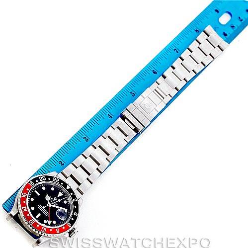 This image shows a full, top-down view of a Rolex GMT-Master 16710 Men's Stainless Steel Black Dial 16710 Men's Stainless Steel Black Dial watch alongside a blue ruler.