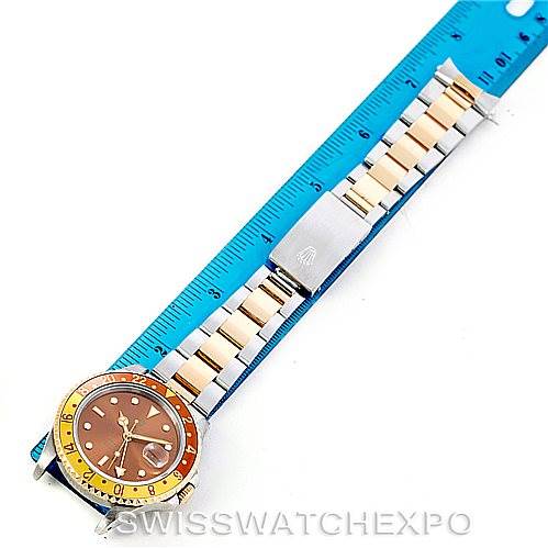 The image shows a Rolex GMT-Master 16713 Men
s Stainless Steel Brown Dial 16713 Men
s Stainless Steel Brown Dial watch laid flat next to a ruler, displaying the watch face and metal bracelet.