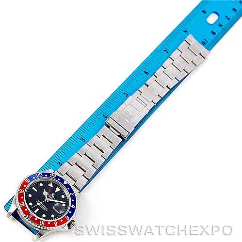 The image shows a top view of the Rolex GMT-Master 16710 Men's Stainless Steel Black Dial 16710 Men's Stainless Steel Black Dial watch alongside a blue ruler.