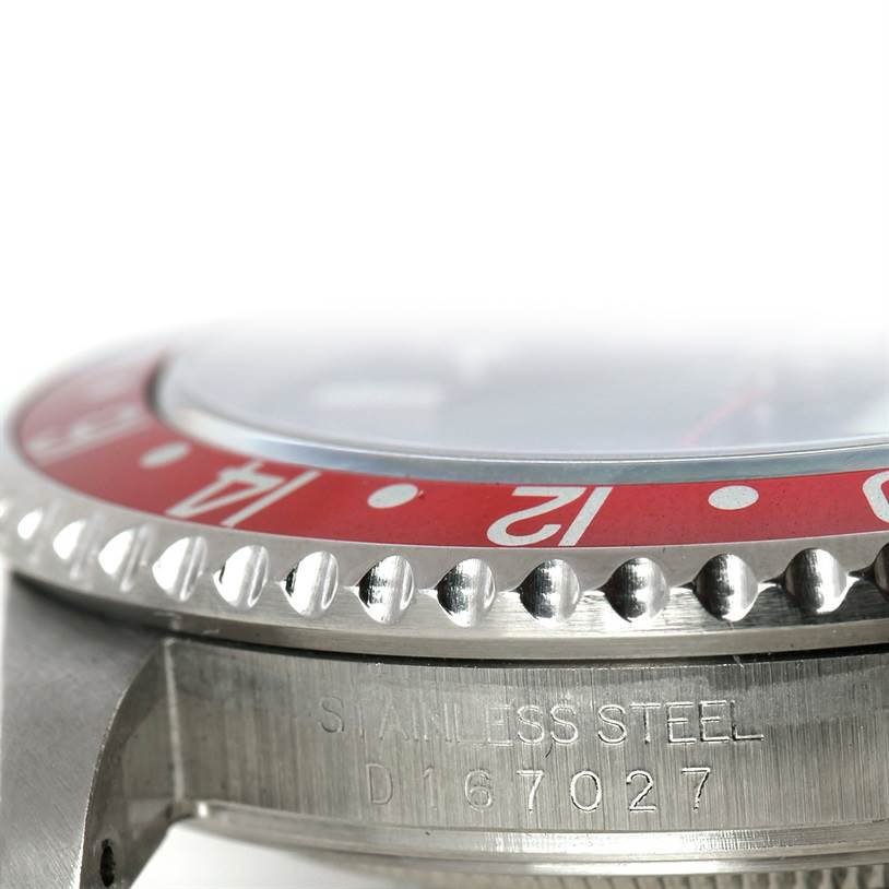 This image shows a close-up side view of a Rolex GMT-Master 16710 Men's Stainless Steel Black Dial 16710 Men's Stainless Steel Black Dial watch, highlighting its red bezel, stainless steel case, and part of its serial number.