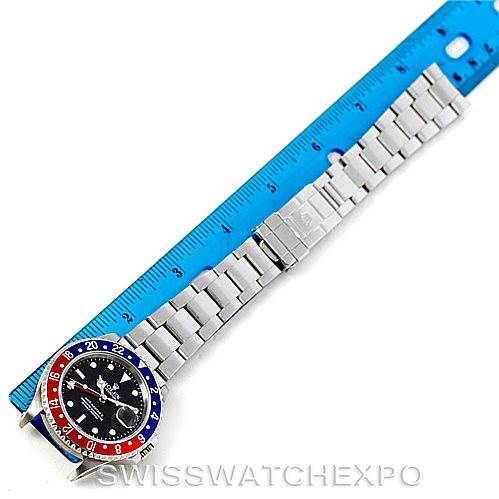 The image shows a top-down view of a Rolex GMT-Master 16710 Men's Stainless Steel Black Dial 16710 Men's Stainless Steel Black Dial watch placed beside a ruler, highlighting its bezel and bracelet.