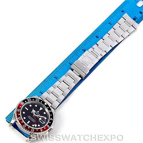 The image shows a Rolex GMT-Master 16710 Men
s Stainless Steel Black Dial 16710 Men
s Stainless Steel Black Dial watch laid flat with its bracelet extended next to a blue ruler.