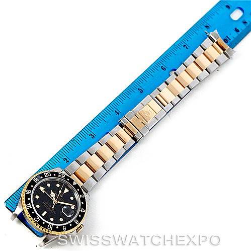 The image shows a Rolex GMT-Master watch laid flat next to a ruler, displaying its face, bezel, and two-tone bracelet.