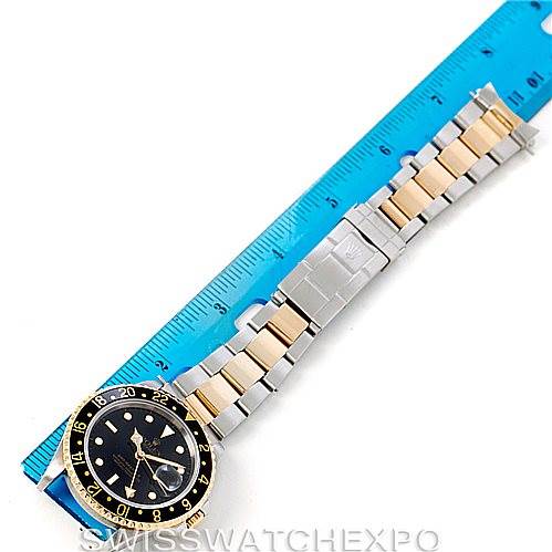 The image shows a Rolex GMT-Master 16713 Men's Stainless Steel Black Dial 16713 Men's Stainless Steel Black Dial watch placed alongside a blue ruler, highlighting the watch face and bicolor metal bracelet.