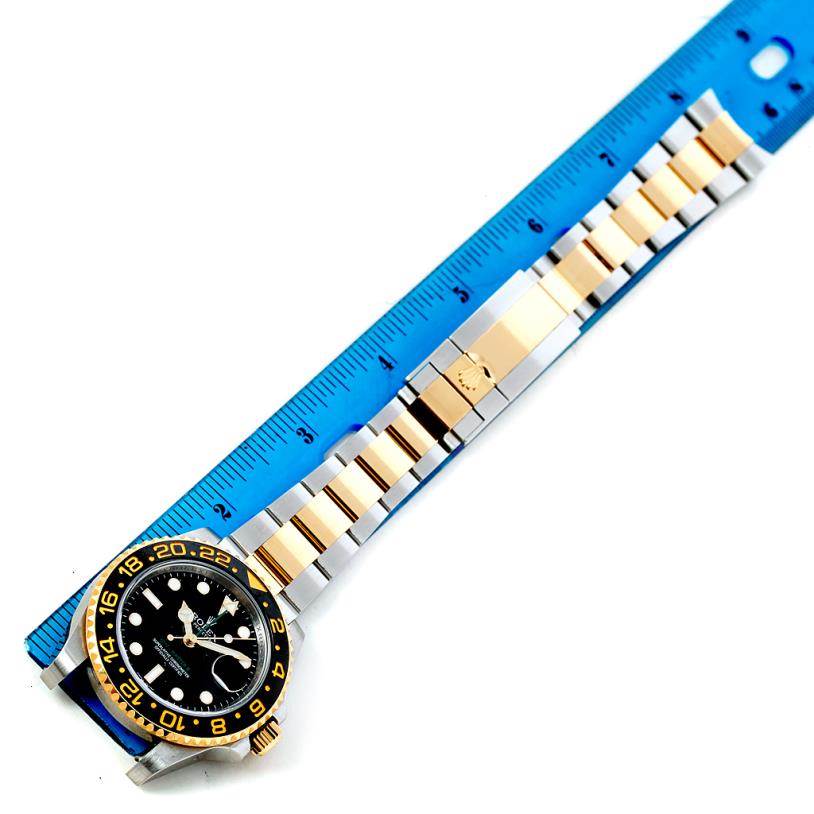The image shows the front view of a Rolex GMT-Master 116713 Men's Stainless Steel Black Dial 116713 Men's Stainless Steel Black Dial watch with a two-tone bracelet next to a blue ruler for scale.