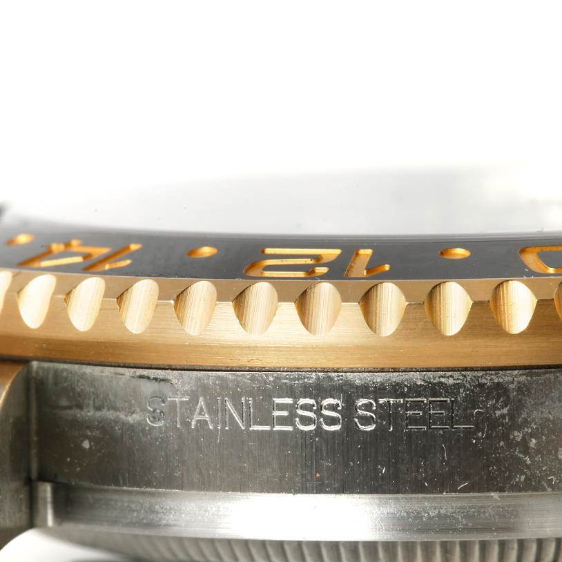 The image shows a close-up of the bezel and part of the case back of a Rolex GMT-Master 116713 Men's Stainless Steel Black Dial 116713 Men's Stainless Steel Black Dial watch, highlighting "STAINLESS STEEL" engraving.