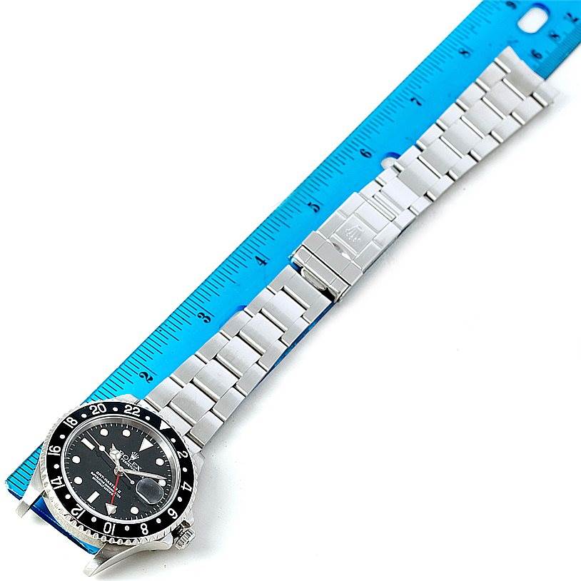 The image shows a top-down view of a Rolex GMT-Master 16710 Men
s Stainless Steel Black Dial 16710 Men
s Stainless Steel Black Dial watch with a metal bracelet, placed next to a ruler for scale.