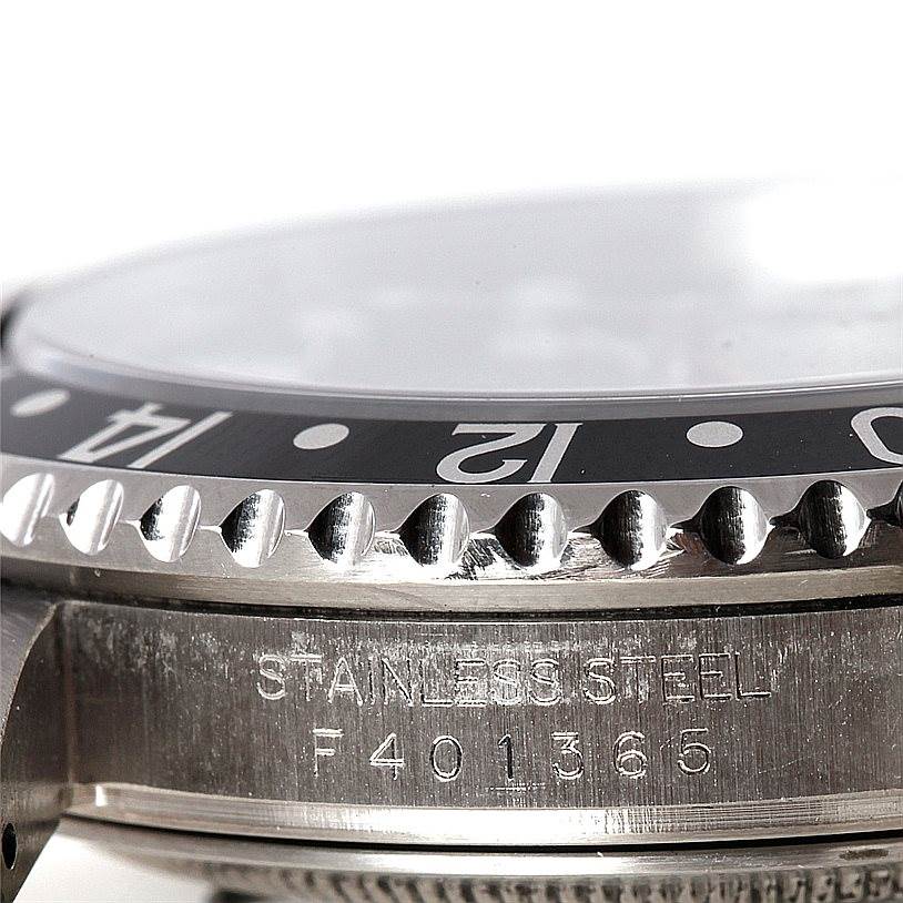The image shows a close-up of the bezel, crystal, and serial number area of a Rolex GMT-Master 16710 Men
s Stainless Steel Black Dial 16710 Men
s Stainless Steel Black Dial watch in stainless steel.