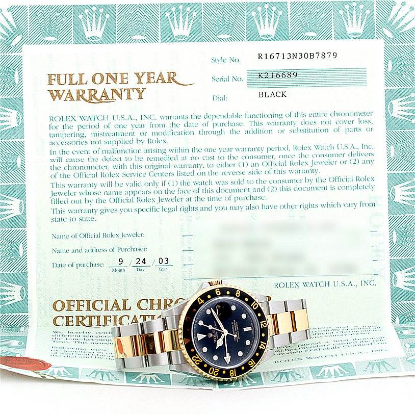 The Rolex GMT-Master 16713 Men's Stainless Steel Black Dial 16713 Men's Stainless Steel Black Dial watch is shown from a top angle, positioned in front of its warranty certificate.