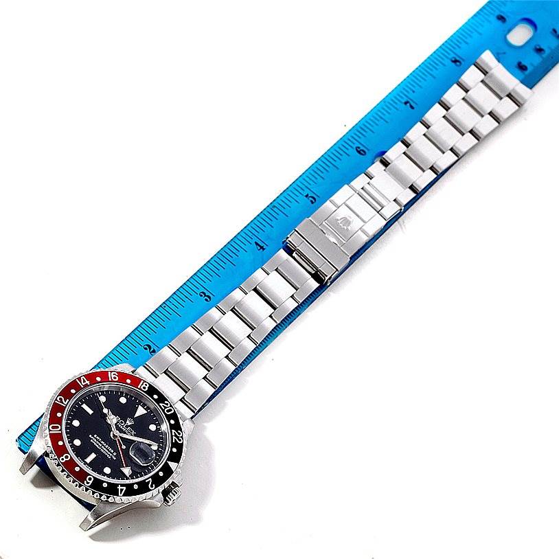 The image shows a top-down view of a Rolex GMT-Master 16710 Men's Stainless Steel Black Dial 16710 Men's Stainless Steel Black Dial watch laid next to a ruler, displaying the face and metal bracelet.