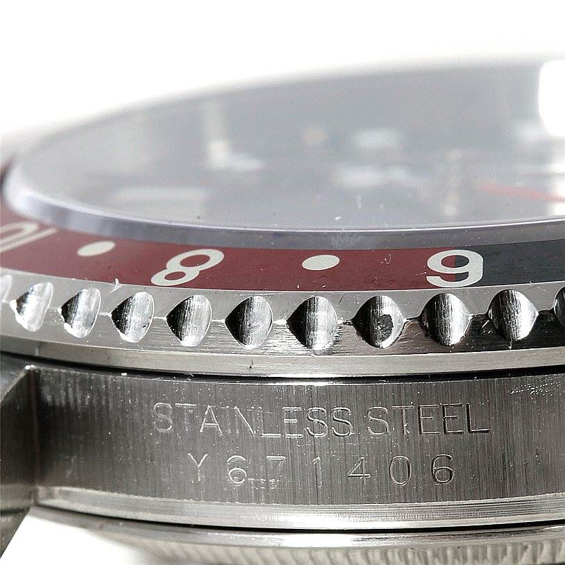 This close-up image of the Rolex GMT-Master 16710 Men's Stainless Steel Black Dial 16710 Men's Stainless Steel Black Dial watch shows its bezel, part of the case, and serial number engraving.