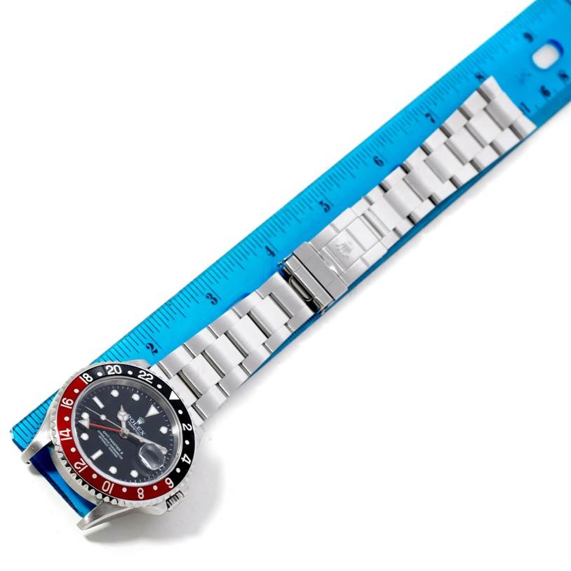 This image shows a top view of a Rolex GMT-Master 16710 Men's Stainless Steel Black Dial 16710 Men's Stainless Steel Black Dial watch with a blue and red bezel, metal bracelet, and a portion of a blue ruler.