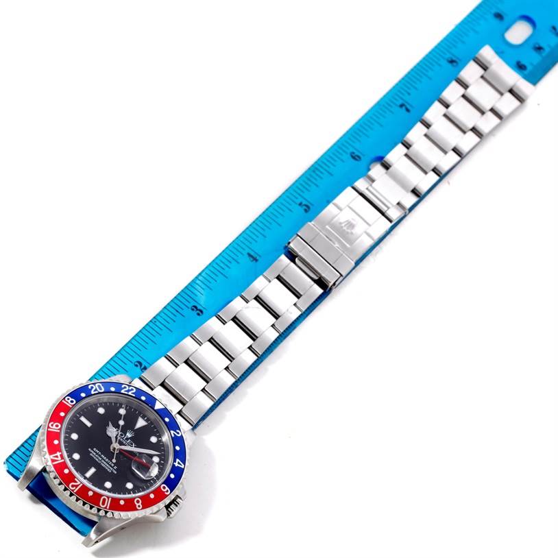 The image shows a Rolex GMT-Master 16710 Men's Stainless Steel Black Dial 16710 Men's Stainless Steel Black Dial watch laid flat next to a ruler, displaying its face, bezel, and bracelet in a top-down angle.