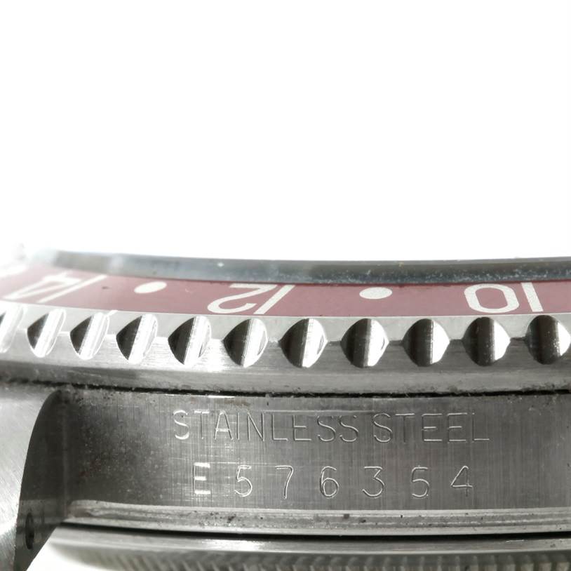 The image shows a close-up angled view of the Rolex GMT-Master 16710 Men's Stainless Steel Black Dial 16710 Men's Stainless Steel Black Dial's bezel and case with visible serial number and "Stainless Steel" engraving.