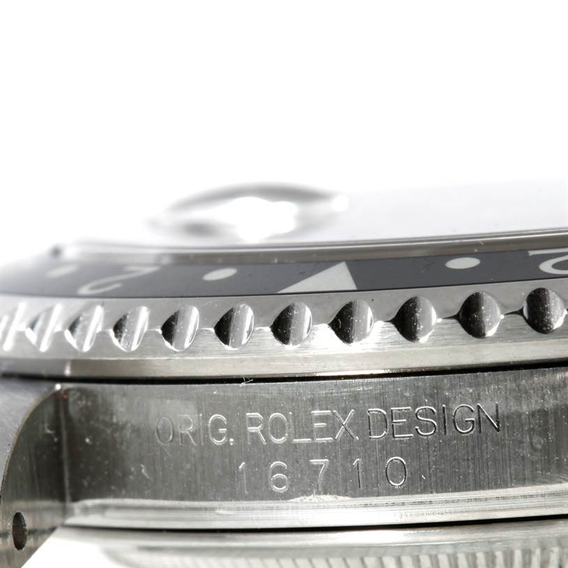 This angled close-up of a Rolex GMT-Master 16710 Men's Stainless Steel Black Dial 16710 Men's Stainless Steel Black Dial watch shows part of the bezel and case, including the model number 16710 on the case side.