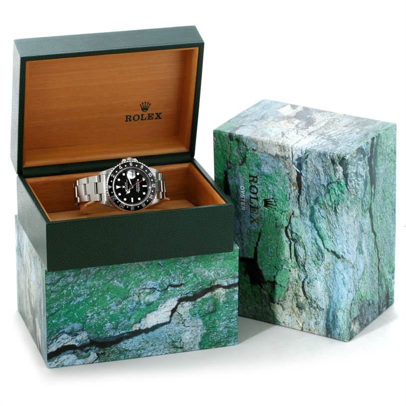 This image shows a Rolex GMT-Master 16710 Men's Stainless Steel Black Dial 16710 Men's Stainless Steel Black Dial watch displayed at an angle in an open green and wooden Rolex box, with its outer packaging beside it.