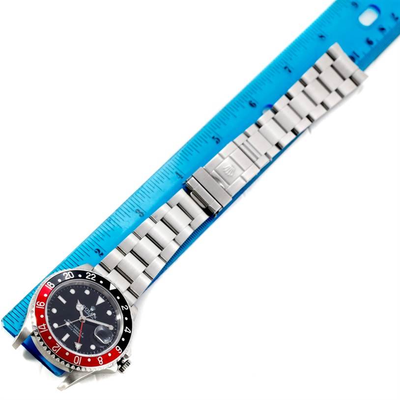 The Rolex GMT-Master 16710 Men's Stainless Steel Black Dial 16710 Men's Stainless Steel Black Dial watch is shown from above, featuring the bezel, dial, and bracelet alongside a blue ruler for scale.