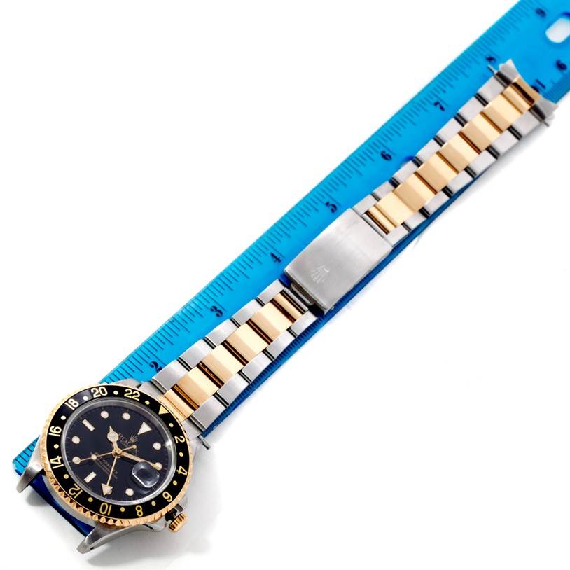 The Rolex GMT-Master 16713 Men's Stainless Steel Black Dial 16713 Men's Stainless Steel Black Dial watch is shown laying flat with its face and bracelet visible against a blue ruler for scale.