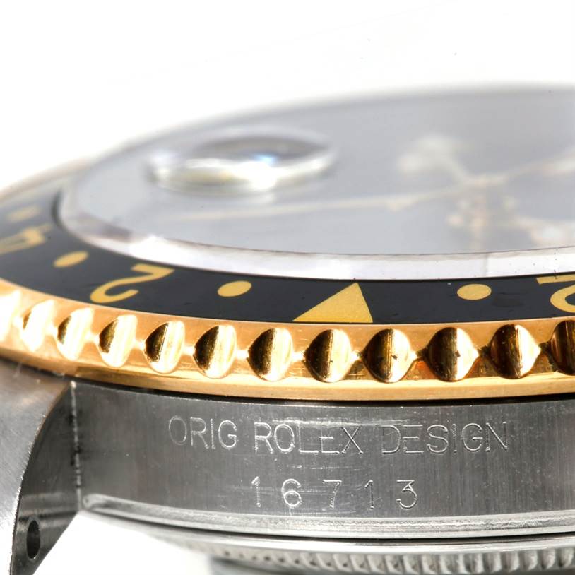 The image shows a close-up of the bezel, crystal, and case side of the Rolex GMT-Master 16713 Men's Stainless Steel Black Dial 16713 Men's Stainless Steel Black Dial watch, focusing on the "ORIG ROLEX DESIGN" engraving.
