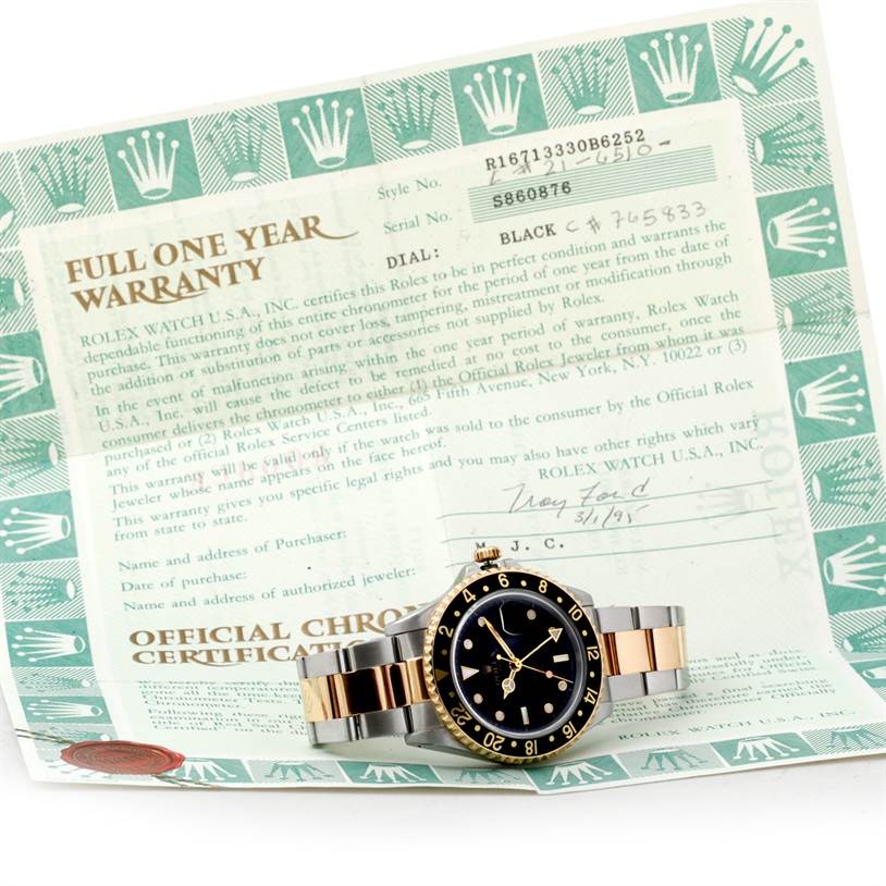 The Rolex GMT-Master 16713 Men's Stainless Steel Black Dial 16713 Men's Stainless Steel Black Dial watch is shown flat on its back, displaying the front, bezel, dial, and bracelet, positioned atop a warranty certificate.