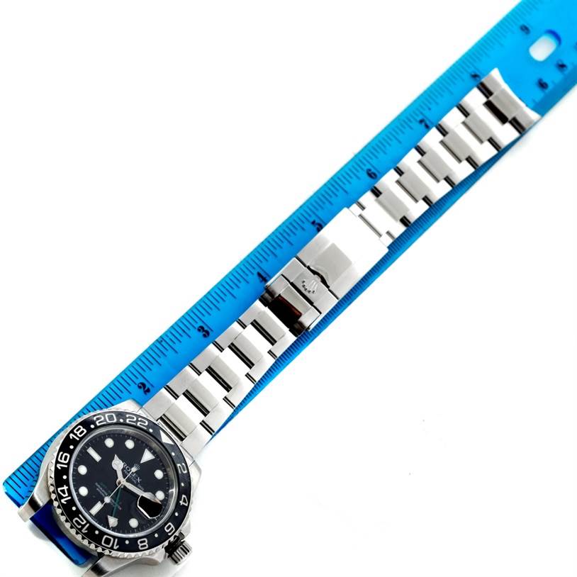 The image shows a silver Rolex GMT-Master 116710 Men's Stainless Steel Black Dial 116710 Men's Stainless Steel Black Dial watch laid flat with its band extended next to a blue ruler.