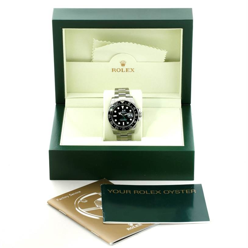 The Rolex GMT-Master 116710 Men's Stainless Steel Black Dial 116710 Men's Stainless Steel Black Dial watch is shown front-facing inside its box, alongside two booklets and a cleaning cloth.