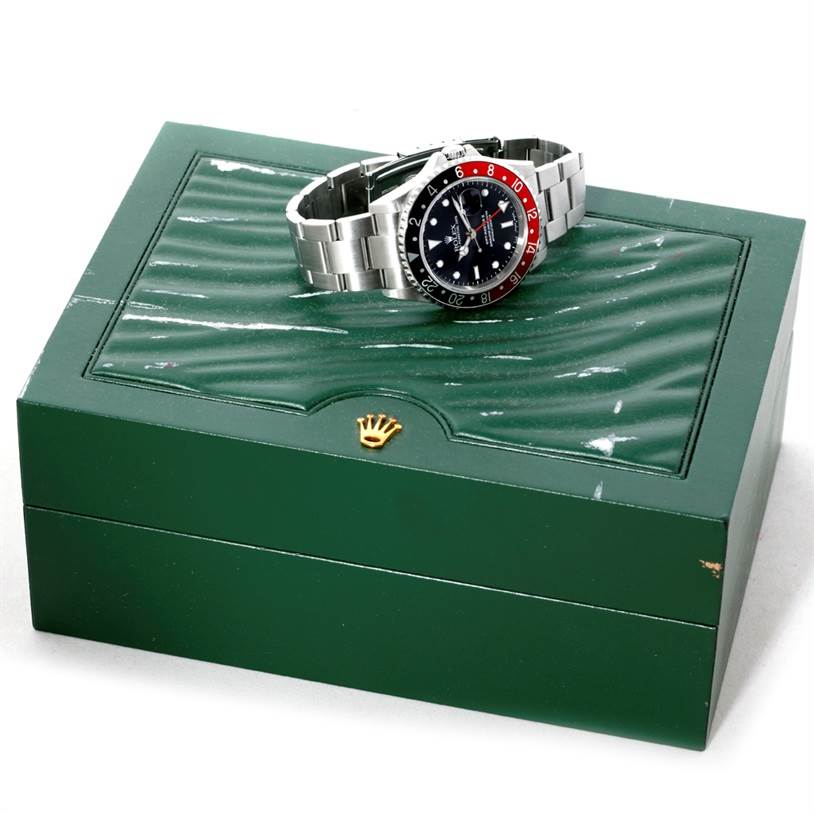The Rolex GMT-Master 16710 Men's Stainless Steel Black Dial 16710 Men's Stainless Steel Black Dial watch is shown angled, highlighting its dial and bezel, placed atop a green Rolex box.